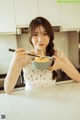 A woman eating a bowl of noodles with chopsticks.