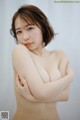 A naked asian woman posing with her arms crossed.