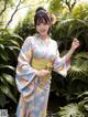 A woman in a kimono holding a flower in her hand.