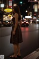 A woman standing in the middle of a city street at night.