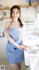 A woman in a blue and white apron standing in a kitchen.