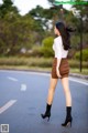 A woman in a white shirt and brown skirt is walking down the street.