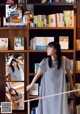 A woman standing in front of a bookshelf holding a book.