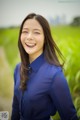 A woman in a blue shirt smiles at the camera.