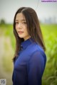 A woman in a blue shirt standing in a field.