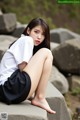 A woman sitting on a rock with her legs crossed.