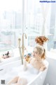 A woman sitting in a bathtub holding a bottle of orange juice.