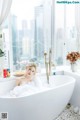 A woman sitting in a bathtub in front of a window.