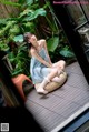 A woman in a blue dress sitting on a wicker chair.