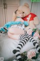 A woman laying on a bed with a teddy bear.