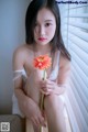 A woman sitting on a window sill holding a flower.