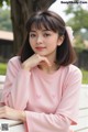 A woman sitting on a bench wearing a pink shirt.