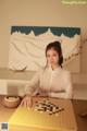 A woman sitting at a table playing a game of checkers.