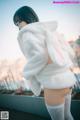 A woman in a white bunny suit is posing for a picture.