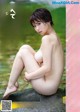 a naked asian woman sitting on a rock in the water