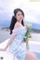 A woman in a blue and white dress holding a bouquet of flowers.