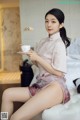 A woman sitting on a bed holding a cup of coffee.