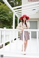 A woman in a red hat is standing on a porch.