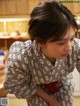 A woman in a black and white kimono standing in a kitchen.