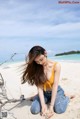 A woman sitting on the sand on a beach.