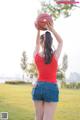 A woman in shorts and a red shirt holding a basketball.